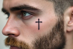 A simple dot-style cross binked in deep black under the other eye on man face under a man’s right eye. tattoo idea