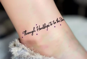A simple black-ink tattoo wraps “Through Hardships To the Stars” around the ankle, with each word nestled between tiny violet stars. S tattoo idea