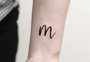 A handwritten "M" in ink-wash black, giving it a natural, imperfect flow. tattoo idea