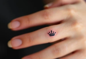 Tiny finger tattoos with black ink crown icons—spiky for king, rounded for queen. tattoo idea