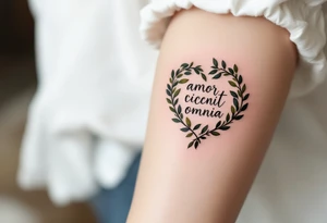 "Amor Vincit Omnia" (Love conquers all) in soft cursive lettering, placed inside a delicate heart made of olive branches, inked in charcoal black with touches of olive green. tattoo idea