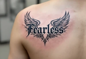 “Fearless” in steel gray Gothic style, flanked by wing motifs in faded charcoal. tattoo idea