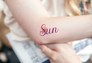 Word "Sun" written vertical with sunflower in pink tattoo idea