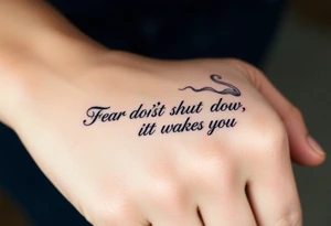 "Fear doesn’t shut you down, it wakes you up" engraved in an elegant script, surrounded by subtle abstract smoke tattoo idea