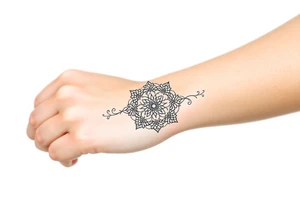 A delicate lace armband going fully around hand in a mandala style, incorporating intricate, circular details tattoo idea