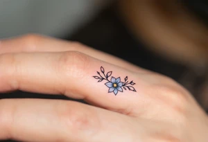 A minimalist black "S" outlined with fine-line flowers in soft pastel tones on finger. tattoo idea