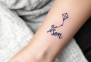 A line-art drawing of a child flying a kite, with the kite string forming the son’s name in dark navy ink. tattoo idea