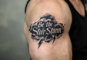 "Be the Storm" in sharp serif font, black ink with storm cloud shading and lightning bolt details in gray. tattoo idea