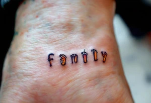The word family beneath a row of tiny matching footprints in soft earth tones. tattoo idea