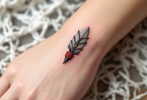 A hand-carved flint arrowhead in gray with red cord wrapping, symbolizing strength and survival tattoo idea