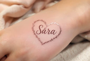 A heart shaded in rose gold with Sára in a handwritten-style font inside. tattoo idea