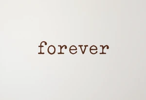 A simple "forever" in lowercase typewriter font with a muted brown ink, vintage style. tattoo idea
