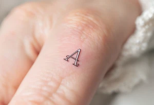 A minimalist outline "A" in soft gray with a blush pink inner fill on a finger. tattoo idea