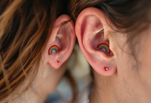 Tiny matching rainbow hearts behind ear of each partner to honor love in every shade. tattoo idea