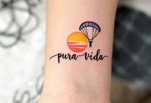 Cursive “Pura Vida” trailing behind a paragliding silhouette against a sunset gradient of yellow, orange, and magenta. tattoo idea