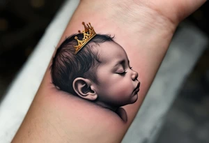 Profile portrait of a baby girl’s sleeping face with a tiny gold crown, shaded in grayscale with realistic detail. tattoo idea