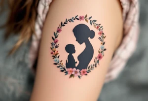 A silhouette of a mother and child in black ink encircled by a floral wreath in pastel hues represents nurturing and tenderness. tattoo idea