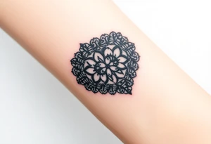 A heart-shaped lace pattern in black and silver, with a delicate filigree border tattoo idea
