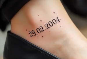 Hand-drawn date 29.02.2004 in a faded graphite tone with small stars scattered around it. tattoo idea