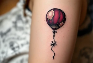 Tim Burton’s lost balloon floats above tombstones, deep maroon with stitched patches and a frayed black string. tattoo idea
