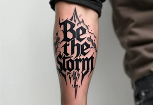 "Be the Storm" in sharp serif font, black ink with storm cloud shading and lightning bolt details in gray. tattoo idea