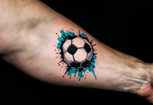 A small behind-the-ear soccer ball tattoo in black with a splash of teal paint. tattoo idea