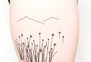 A field with long grass and flowers with mountains in the background tattoo idea