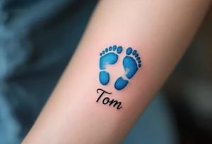 A pair of tiny blue footprints with the son's name Tom in elegant black script beneath. tattoo idea