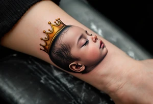 Profile portrait of a baby girl’s sleeping face with a tiny gold crown, with realistic detail. tattoo idea