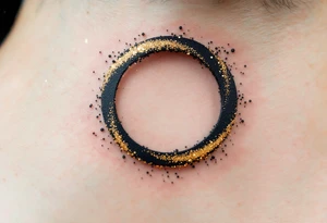 A solid black circle surrounded by a thin halo of gold dust speckles. tattoo idea