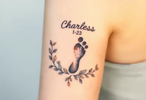 baby footprint print with the name Charles above it, the date 1-14-23 below it and surrounded by floral vines on a forearm tattoo idea