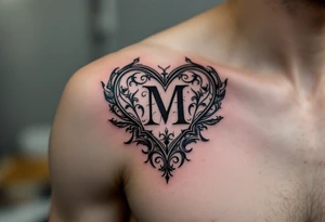 A black and grey ornamental heart with a bold Gothic-style letter "M", surrounded by subtle shading and filigree details. tattoo idea