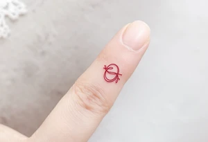 A tiny, delicate red band looped around the finger tattoo idea