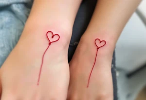 One wears a heart with red string of fate, the other the string continuing into their hand, connecting both wrists. tattoo idea