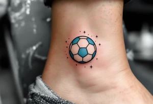 A small ankle tattoo of a pastel blue soccer ball with sparkles around it for a playful look. tattoo idea