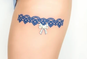 A delicate lace garter tattoo in deep royal blue, adorned with a small white satin bow and pearl centerpiece tattoo idea