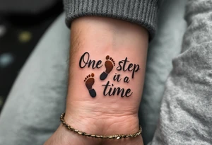 “One step at a time” in warm brown handwritten font with footprint silhouettes fading in earthy tones. tattoo idea