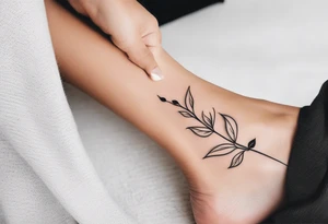 delicate feminine tattoo, plant stem ornament with leaves and shading around the ankle with an overlap on the foot.  at the ends of the stem the letters D, K tattoo idea
