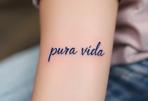 Simple cursive “Pura Vida” inked in navy blue with a small lavender sprig underlining the text. tattoo idea