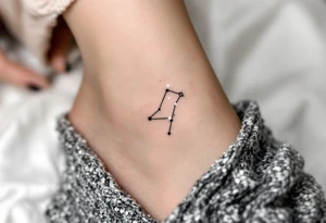 A tiny constellation in white glows from inside a black-ink outline of scales on the ankle. tattoo idea