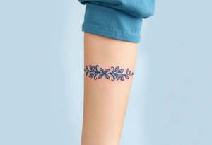 A lace ribbon around the forearm, with fine embroidery-inspired details tattoo idea