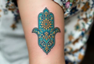 A vibrant turquoise and gold Hamsa with delicate filigree, radiating a mystical and regal aura. tattoo idea