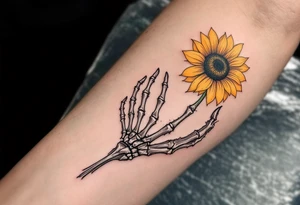 A skeleton hand holding a dying yellow sunflower, "memento mori" in thin, winding black cursive along the stem. tattoo idea