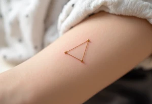 Three gold ink dots placed behind the ear in a triangle, inspired by celestial navigation and guidance. tattoo idea