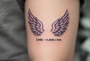 pair of angel wings enclosing "Linda – 1.1.2016 v 0:01", done in light gray and faded lilac. tattoo idea