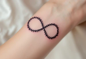 A lace-textured infinity outline in dark gray, with a soft burgundy heart sewn into the design. tattoo idea