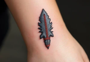 A hand-carved flint arrowhead in gray with red cord wrapping, symbolizing strength and survival tattoo idea