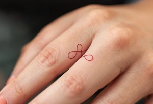 A tiny, delicate red band looped around the finger tattoo idea