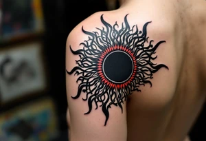 A bold black Celtic sun tattoo with red accents radiates tribal power across the upper shoulder. tattoo idea