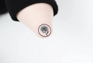 Small black ink tattoo with full moon, small chrysanthemum and tiny scorpio gliph inside moon tattoo idea